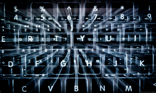 A stylized photo of a backlit keyboard with multiple overlapping ghostly photos of itself overlayed.