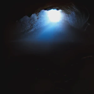 Picture of a dark cave with sunlight streaming in. Cover generated by craiyon.com.