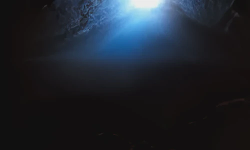 Picture of a dark cave with sunlight streaming in. Cover generated by craiyon.com.